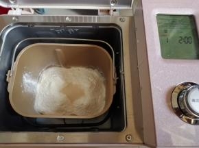 把水、蛋液、糖和盐（对角放）、奶粉、面粉和酵母都倒入面包桶里，如果室温高的话，就需要用冰水和面。把面包桶放入到东菱JD08面包机里，启动和面程序10分钟