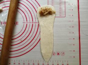 再擀成上面宽，下面尖的形状，并在上面摆上肉松