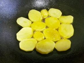不粘锅中倒多点油，放入土豆片煎至两面金黄变硬。
