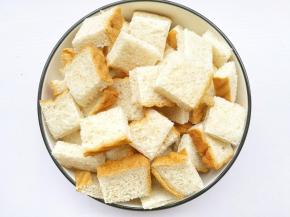 烤箱160℃预热10分钟，土司横竖各切三刀，将土司切成小块，椰子油加热融化。