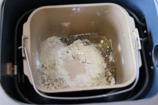 四周再倒入奶粉和意式香草，粉中间挖个洞放入干酵母粉，启动面包机和面程序开始揉面，揉面程序结束后选择发酵程序开始发酵；