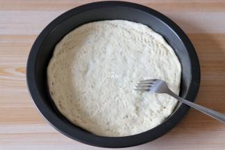 将发酵好的面团一分为二，用擀面杖分别擀成跟披萨盘差不多大小的圆形，放入盘内，让面团完全贴合四周，用叉子在面团上叉一些小孔，避免面团在烤的时候鼓起来（此配方可以做两个薄底披萨，喜欢厚底的就不用将面团一分为二，做一个就行）；