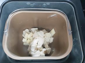 取出面团切成小块或者用剪刀剪成小块，同时把软化好的黄油一并放入面包桶内，然后再放回面包机，再次设置一个MIX程序。