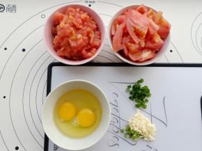 西红柿去皮一个切丁，一个切块。鸡蛋打散，小葱和蒜切碎。