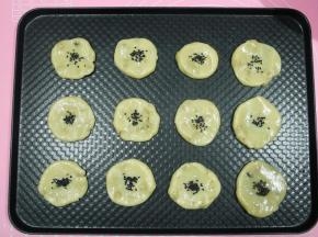 按扁，不需要按太扁，中间要留空，烘烤会膨胀，正好一盘12个。然后在面团中间位置刷一层全蛋液，撒上芝麻。