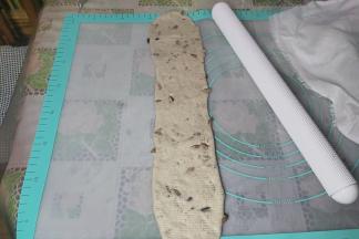 取一个擀卷的面团，再次擀成长舌状，不要来回擀，在中间固定，然后用擀面杖朝两边拉长，长度要比之前长一些。