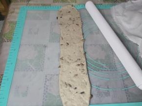 取一个擀卷的面团，再次擀成长舌状，不要来回擀，在中间固定，然后用擀面杖朝两边拉长，长度要比之前长一些。