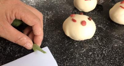 取少许绿面团搓成细长条，在中间切开，再在里侧压成饼皮，在里面压出叶子的纹路