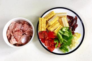 把鸡腿剁块，玉米、青椒、红椒、干辣椒和姜蒜切好。