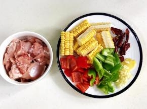 把鸡腿剁块，玉米、青椒、红椒、干辣椒和姜蒜切好。