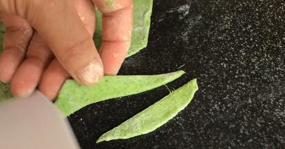 把绿面团擀成面皮，分别切出长叶子和花茎的形状