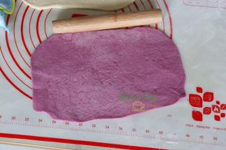 同理，去一个紫薯面团，用擀面杖把紫薯面团擀成大小和白面团一样。