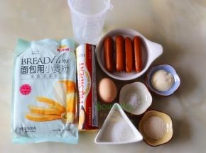以下配料是4个面包食材：金龙鱼面包用小麦粉（高筋小麦粉）140克、牛奶75克、白砂糖20克、黄油15克、蛋液10克、盐1克、干酵母1克、脆皮火腿肠4根
表面装饰：全蛋液适量、白芝麻适量