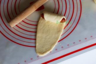 把脆皮火腿肠放在擀好的面片上一端，往上卷至紧实，收口处可以擀的更薄更贴紧。