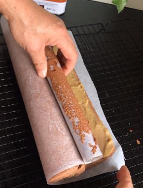 借助擀面杖把油纸卷起，一边把蛋糕卷成卷