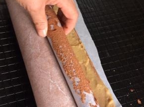 借助擀面杖把油纸卷起，一边把蛋糕卷成卷