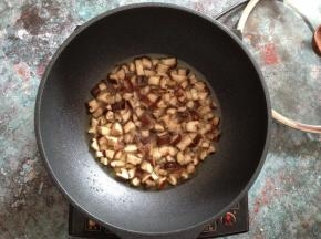 锅内加油烧至4成热倒入香菇丁中小火慢慢炒干水分