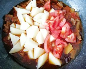 一个小时之后，下入土豆块和剩下的一半西红柿翻炒均匀，继续中小火炖10分钟左右(土豆熟了即可)。