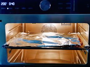 加盖一张锡纸，避免油渍金花四溅，还可以避免羊排表面烤火大，200度石窖烘烤40分钟。