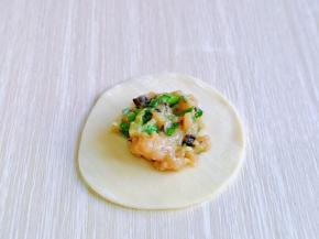 取一张饺子皮，放入馅料，将饺子皮对折。