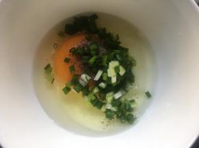 将鸡蛋磕入碗中，倒入香葱碎，调入适量食盐、胡椒粉；