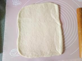 发酵好以后的面团取出排气然后揉圆盖保鲜膜松弛十分钟，松弛好以后擀成长方形。然后切成两指宽的长条4条，把刚才拌匀的黄油炼乳酱涂抹到面片上，抹均匀，再撒上蔓越莓干，把蔓越莓干稍微按压一下，以防后面会掉落。（炼乳不要都用完，后面还要刷面用。）