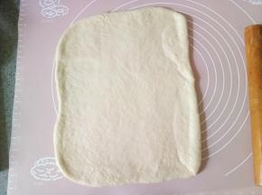 发酵好以后的面团取出排气然后揉圆盖保鲜膜松弛十分钟，松弛好以后擀成长方形。然后切成两指宽的长条4条，把刚才拌匀的黄油炼乳酱涂抹到面片上，抹均匀，再撒上蔓越莓干，把蔓越莓干稍微按压一下，以防后面会掉落。（炼乳不要都用完，后面还要刷面用。）