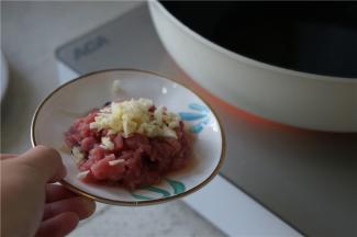 锅里加油预热好，将蒜粒及肉丁下锅爆香。