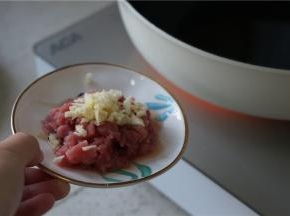 锅里加油预热好，将蒜粒及肉丁下锅爆香。