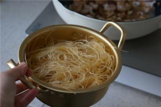 然后将挂味的粉丝也下锅，粉丝下锅之后用筷子慢慢划散，让粉丝将锅里那点少许的汤汁吸附掉。