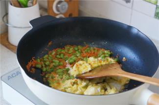 再将青豆及胡萝卜划至一边，再加入蛋液，炒至蛋液凝固。