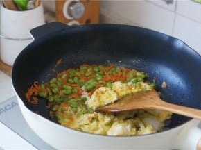 再将青豆及胡萝卜划至一边，再加入蛋液，炒至蛋液凝固。