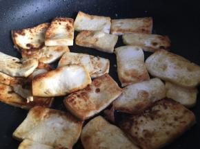 豆腐全部放入锅中后，开中小火慢煎，并时不时晃动煎锅使其受热均匀，不建议用锅铲操作，这样容易让豆腐碎掉。煎至豆腐底部边缘变黄变煎颜色变深后，再用锅铲小心翻面。每家锅具不一致，但是请注意中间与边缘豆腐的受热情况，并适当进行受热调整，最后根据自己喜欢的煎豆腐程度进行翻面或者下一步操作；