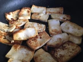 豆腐全部放入锅中后，开中小火慢煎，并时不时晃动煎锅使其受热均匀，不建议用锅铲操作，这样容易让豆腐碎掉。煎至豆腐底部边缘变黄变煎颜色变深后，再用锅铲小心翻面。每家锅具不一致，但是请注意中间与边缘豆腐的受热情况，并适当进行受热调整，最后根据自己喜欢的煎豆腐程度进行翻面或者下一步操作；