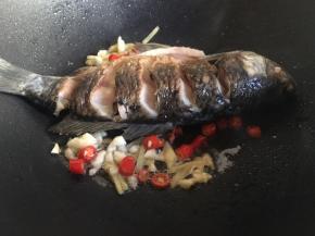 鱼煎好后，往鱼两边放入姜丝、辣椒，不用翻拌爆出香味；
