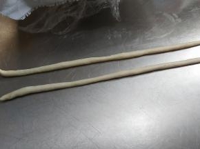 取出两块小面团，轻轻搓成两头尖的长条。