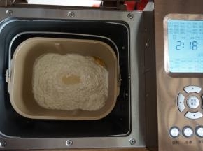 在面粉顶端加入酵母，将面包桶放入到面包机里，选择甜面包程序，时间显示2小时18分钟（不同型号的面包机制作时间有所不同）