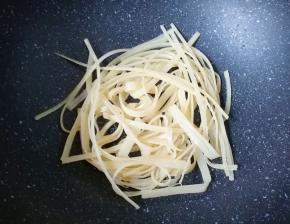 不粘锅倒入少许食用油烧热，下入冷面炒至变软。