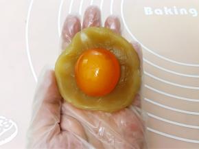 莲蓉馅分为25克一个，取一份包入一个咸蛋黄收口滚圆