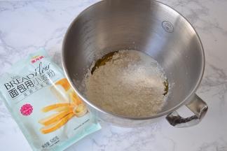 将黄油、盐除外的全部材料，面粉、牛奶、蛋液、糖，酵母按顺序放入盆内。您可以用面包机，也可以用厨师机，或者用手揉。每种面粉的吸水率不同，所以水要预留出10克，根据面团实际情况增减。我用的是金龙鱼面包用小麦粉，它是以100%优质进口小麦为原料，筋力高，做出的面包组织细腻，口感松软，弹性足，不仅适用于面包机面包的制作，也适用于各种手工面包的家庭制作， 我一直使用它。