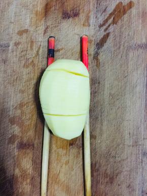 土豆削皮洗净，下面垫两根筷子，切成薄片！注意不要切断了哦！