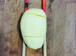 土豆削皮洗净，下面垫两根筷子，切成薄片！注意不要切断了哦！