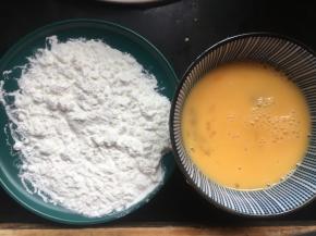 然后准备一个盘子，倒入一层薄薄的淀粉，再将鸡蛋磕入一个碗中打散；