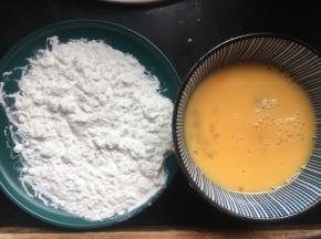 然后准备一个盘子，倒入一层薄薄的淀粉，再将鸡蛋磕入一个碗中打散；