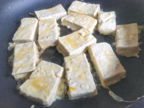 将锅子烧热，倒入适量食用油，平铺放入豆腐块，中小火慢煎；
