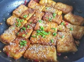 汤汁快收干时均匀撒入芝麻和葱花，装盘出锅即可；