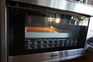 将拌好的蛋糕糊倒入铺有油纸的正方形烤盘里，刮平表面，在桌面上震出气泡，烤箱提前10分钟预热到170度，放入烤盘，烘烤18分钟左右（实际烘烤温度要根据自家烤箱脾气而定）。烘烤结束，将蛋糕取出，晾3分钟后立即倒扣在晾架上，趁热撕去底部的油纸，晾凉