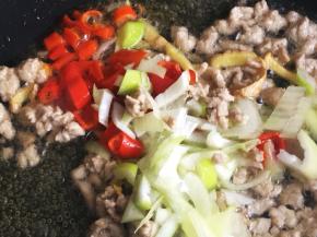 放入红辣椒、葱花继续翻炒出香味。