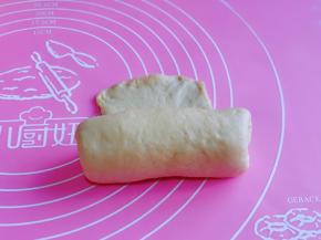 取一块面团，用擀面杖擀长舌状，将气泡拍破，由上而下卷起。