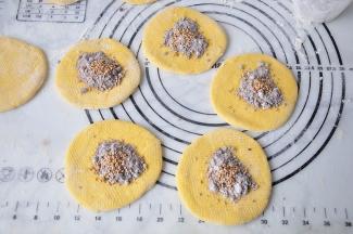 在切好的小剂子上散面粉，用擀杖将面段棍擀成面皮。放入红糖与面粉混合好的糖馅，并且撒上芝麻。红糖和面粉的比例按照3：1就可以